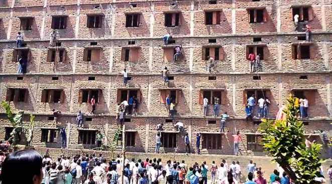 Parents and guardians climbing up on the school building to pass the chit papers with answers written on them of the questions that has been asked in exam. Picture Courtesy: Prashant Ravi